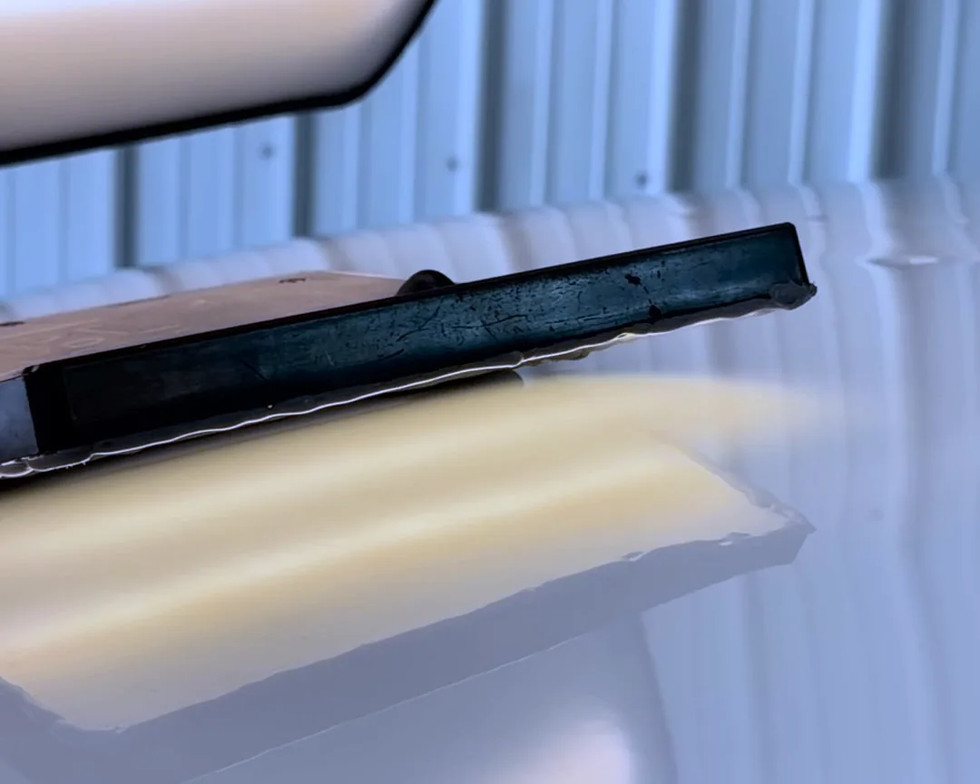 A PDR tool resting on white paint, with the light of a reflection board laid across the panel